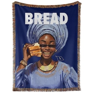 May include: A woven throw blanket featuring a dark blue background and the word BREAD in large white letters. The design depicts a smiling individual wearing a light blue headwrap, sunglasses, and gold jewelry, holding a stack of bread slices.