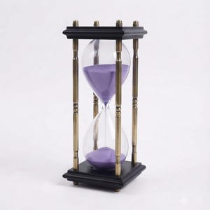 May include: An hourglass featuring a clear glass bulb filled with purple sand, held within a frame composed of four vertical brass-toned metal pillars and square black wooden top and bottom plates with small feet at the base.