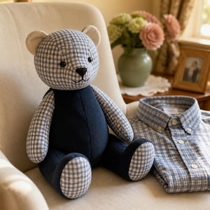 May include: A stuffed teddy bear crafted from blue and white gingham fabric with a solid navy blue corduroy torso and leg sections. The bear features black button eyes, a stitched black nose and mouth, and cream-colored inner ear accents.