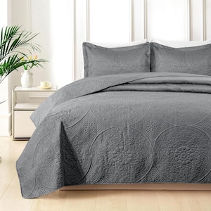 May include: A charcoal gray bedspread and two matching pillow shams featuring an embossed circular medallion pattern. The bedding set has a quilted texture with intricate floral and geometric details throughout the fabric surface.