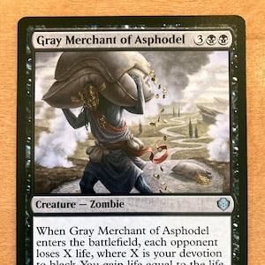 May include: A black and white illustration of a zombie creature carrying a sack of coins. The card is titled "Gray Merchant of Asphodel" and has a mana cost of 3 black mana symbols. The creature has a power of 2 and a toughness of 4. The card text reads: "When Gray Merchant of Asphodel enters the battlefield, each opponent loses X life, where X is your devotion to black. You gain life equal to the life lost this way. (Each in the mana costs of permanents you control counts toward your devotion to black.)"