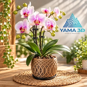 May include: A potted Phalaenopsis orchid with light pink and white petals and a deep magenta centre, supported by black stakes. The plant sits in a tan, 3D-printed lattice-patterned planter with a black saucer. The logo YAMA 3D is visible.