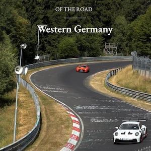 Peut inclure: Une couverture de livre intitulée ATLAS OF THE ROAD Western Germany présentant une photographie d'un circuit avec une voiture de sport blanche au premier plan et une voiture de sport orange au loin. La piste a des bordures rouges et blanches.