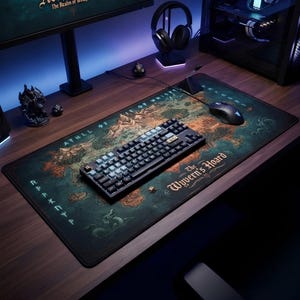May include: A rectangular desk mat featuring a fantasy map illustration in shades of teal, green, and orange. The text "The Wyvern's Hoard" and "Athll" are printed on the surface. A black mechanical keyboard and a black computer mouse are placed on top.