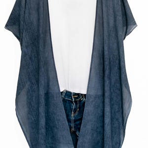 May include: A denim blue kimono-style cover-up with short sleeves, layered over a white t-shirt and blue jeans. The cover-up has a flowing, open design. The text "| DENIM BLUE" is in the upper right corner.