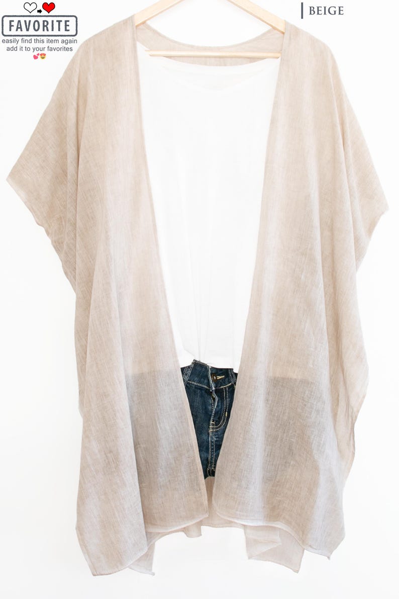 May include: A beige linen kimono-style cover-up draped over a white t-shirt and denim shorts. The cover-up is lightweight and has wide sleeves. The word "FAVORITE" is in a white box with a heart icon.