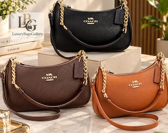 Puede incluir: Tres bolsos de hombro Coach en cuero negro, marrón oscuro y tostado, cada uno con una correa de cadena de metal dorado, cierre de cremallera superior y un logotipo de Coach dorado en la parte delantera. Cada bolso incluye una etiqueta de cuero.