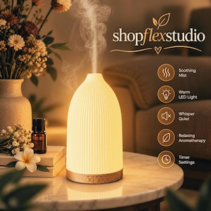 Puede incluir: Un difusor de aceites esenciales blanco, acanalado y en forma de cúpula que emite un chorro vertical de niebla. La base es de tono madera clara con botones de control. El texto dice shopflexstudio, Soothing Mist, Warm LED Light, Whisper Quiet, Relaxing Aromatherapy, Timer Settings.