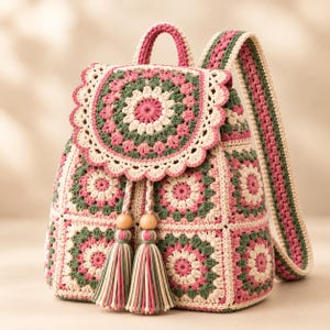 Könnte beinhalten: Ein gehäkelter Rucksack mit einer runden Mandala-Klappe und quadratischen Granny-Motiven in Creme, Salbeigrün und Altrosa. Der Rucksack verfügt über einen Tragegriff, verstellbare Schultergurte und einen Kordelzug mit zwei Holzperlen.