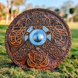 May include: A circular wooden shield featuring intricate relief carvings of intertwined dragon motifs and geometric patterns. The centre is dominated by a polished, convex metal boss secured with rivets, surrounded by a dark stained wood finish.
