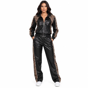 Puede incluir: Un conjunto de chándal de piel sintética negra que incluye una chaqueta con cremallera y pantalones a juego. La chaqueta tiene paneles con estampado de leopardo en hombros y mangas, y los pantalones llevan franjas laterales de leopardo.