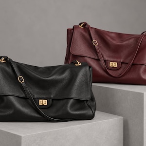 May include: Two leather shoulder bags, one in black and one in deep burgundy, each featuring a textured surface, a fold-over flap with a gold-tone rectangular turn-lock closure, and an adjustable shoulder strap with gold-tone metal hardware.