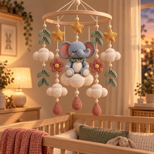 May include: A nursery mobile featuring a central crocheted blue elephant sitting on a white cloud. The mobile includes yellow crocheted stars, white clouds, green leaves, pink flowers, and pink teardrop shapes suspended from a circular wooden frame.