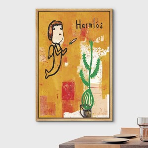 May include: A framed wall art print featuring a yellow background with abstract red and white patches. A cartoon-style figure with wings and a small knife is depicted next to a green cactus in a pot. The text "Harmlos" is written in black ink.