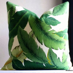 May include: A white pillow with a green tropical leaf pattern. The leaves are large and have a realistic texture.