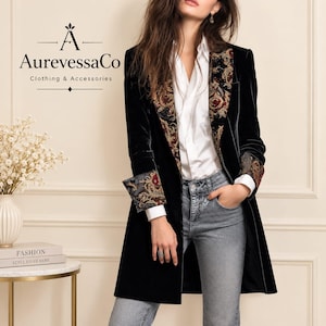 May include: A black velvet blazer featuring a white button-down shirt and blue jeans. The blazer has wide lapels and cuffs decorated with a multi-colored floral and paisley pattern. The text AurevessaCo Clothing & Accessories is visible.