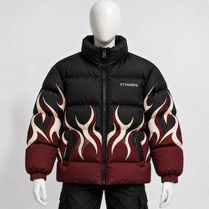 Puede incluir: Una chaqueta acolchada negra con cuello alto y cremallera frontal completa. La prenda presenta un patrón de llamas en color crema y rojo oscuro en el pecho y las mangas. El texto STYNORPK está impreso en blanco en la parte superior izquierda.