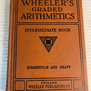 Puede incluir: Un libro antiguo titulado "Wheeler's Graded Arithmetics" con una cubierta naranja y texto negro. El libro es un "Intermediate Book" publicado por Wheeler Publishing Co. en Chicago. La portada presenta diseños geométricos.