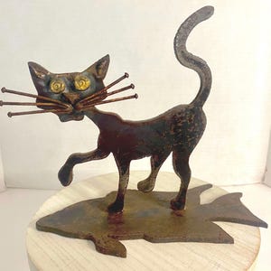 Gato negro de metal, arte popular vintage, brutalista primitivo, gato soldado sobre pez