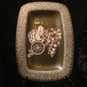 May include: A rectangular serving dish with a green background and a white, gold, and brown fruit design. The dish has a white speckled border.