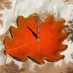 May include: Orange and yellow ceramic leaf-shaped serving dish with a gold rim and a silver handle.