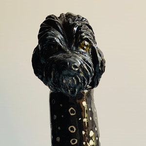 May include: Black ceramic vase with a white polka dot pattern. The top of the vase is shaped like a dog's head.