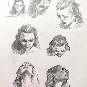 May include: A graphite pencil drawing on paper featuring six distinct sketches of a person's head and shoulders from various angles, including front-facing, profile, and downward-looking perspectives, showcasing detailed shading and facial features.