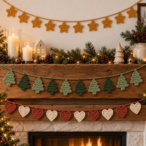 May include: Three crocheted garlands displayed on a wooden mantel. The top garland features mustard yellow stars, the middle garland consists of alternating light and dark green pine trees, and the bottom garland displays red and cream hearts.