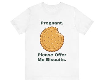 May include: A white short-sleeve t-shirt featuring a graphic of a round, golden-brown biscuit with a bite taken out of it. Above the biscuit is the text 'Pregnant.' and below the biscuit is the text 'Please Offer Me Biscuits.'