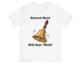 May include: A white short-sleeve t-shirt featuring a graphic of a gold hand bell with a brown handle. The text above the bell reads "Retired Head." and the text below the bell reads "Still Says 'Walk!'" in a dark gray, bold, serif font.