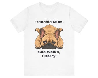 May include: A white short-sleeve t-shirt featuring a graphic of a tan French Bulldog lying flat on its stomach. Above the dog is the text "Frenchie Mum." and below the dog is the text "She Walks, I Carry." in a bold, black sans-serif font.