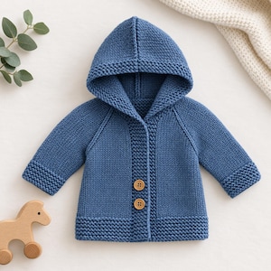 Könnte beinhalten: Eine blaue Strickjacke mit Kapuze, langen Ärmeln mit kraus rechts gestrickten Bündchen, einer passenden Kapuze im Kraus-Rechts-Muster und einer Knopfleiste mit zwei runden Holzknöpfen. Der Körper ist in glatt rechts gestrickt.