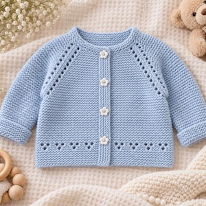 May include: A light blue long-sleeve knit cardigan featuring a round neckline, four white flower-shaped buttons down the center, and decorative eyelet detailing along the raglan sleeves and the bottom hem of the garment.