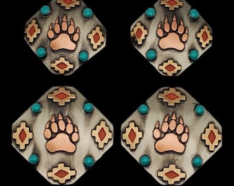 Op de afbeelding: Zes zilverkleurige zeshoekige metalen knopen met een koperkleurige beerpootafdruk in het midden. Elke knop is versierd met een geometrisch patroon in turquoise en rood.