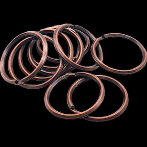 May include: A pile of copper-colored key rings. The rings are all the same size and are arranged in a random pattern.