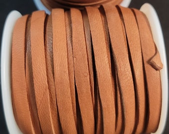 May include: A spool of 3/16 inch wide, 50 foot long, saddle tan deerskin lace. The label reads "Real Leather Crafts" and "DOS31650 0271 Deerskin Lace 3/16 x 50 ft Saddle Tan 2016-06 Spl Made in USA".