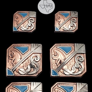 以下が含まれることがあります： 青、銀、銅のデザインが施された正方形の金属ボタン6個セット。各ボタンには、スタイリッシュな矢印と花柄が描かれています。