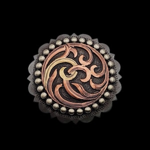 May include: A detailed, round metal object with a central design of swirling copper, gold, and bronze tones. The design is set against a dark, textured background and surrounded by a ring of small, silver-colored beads. The outer edge has a scalloped design.