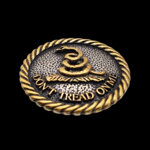 May include: A gold and silver round button with a coiled snake and the text "Don't Tread On Me".