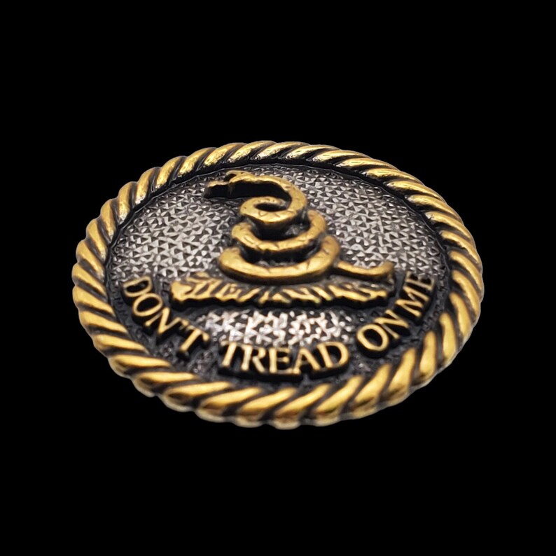 May include: A gold and silver round button with a coiled snake and the text "Don't Tread On Me".