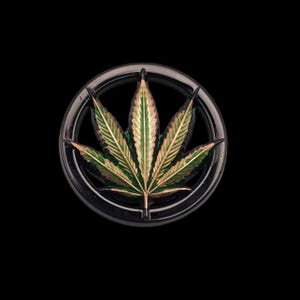 May include: A round, black metal emblem featuring a detailed green and gold cannabis leaf design. The leaf is centered within a circular frame, set against a solid black background. The emblem has a glossy finish.