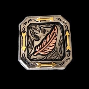 以下が含まれることがあります： 銀色の金属製ベルトバックル。中央には銅色の羽のデザインがあり、詳細な彫刻模様で囲まれています。バックルの縁には金色の矢が配置されています。