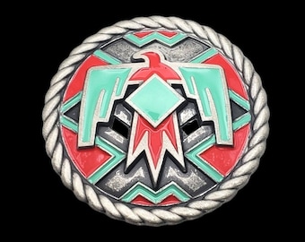 May include: A silver-toned metal belt buckle with a red, green, and turquoise design of a stylized eagle. The eagle is surrounded by a rope-like border.