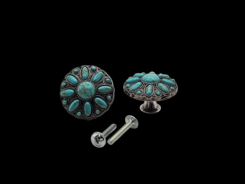 Może przedstawiać: Dekoracyjne gałki do szafek ze srebrnym wykończeniem i turkusowymi kamieniami. Gałki mają kwiatowy wz&oacute;r i są dostarczane ze śrubami montażowymi. Gałki są pokazane na czarnym tle.