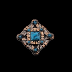 May include: A copper-toned metal pin with a geometric design featuring a central turquoise stone and six smaller turquoise stones around it.