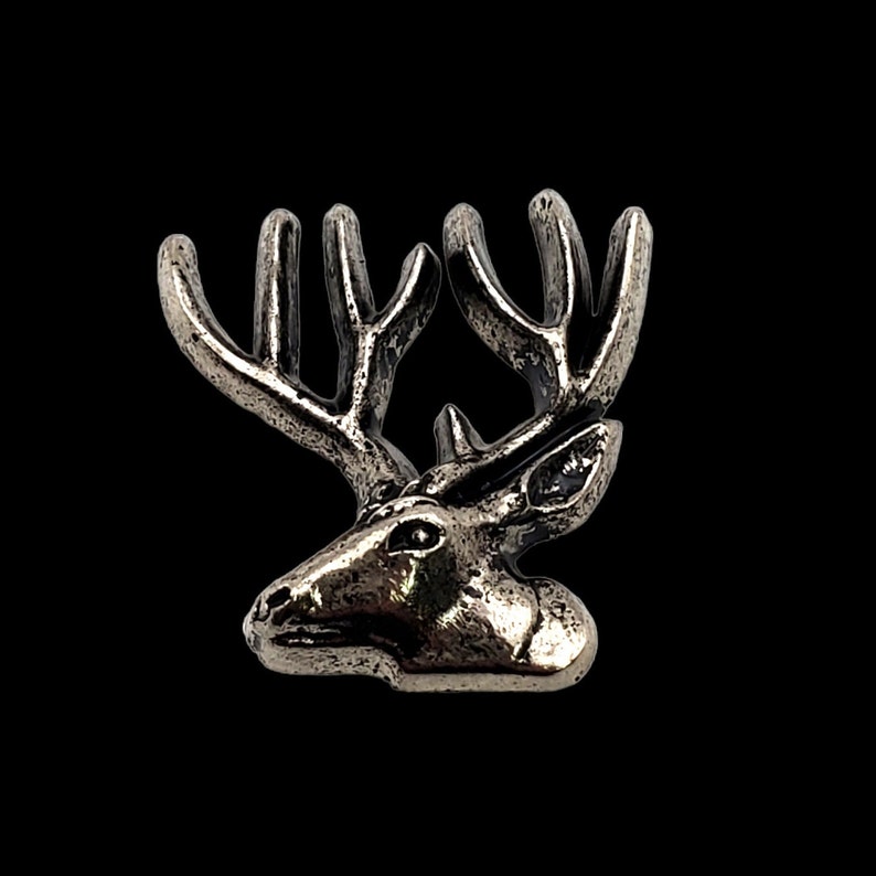 May include: A silver-toned deer head with antlers, a detailed and realistic sculpture.