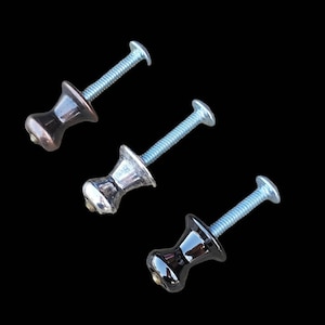 May include: Three cabinet knobs with different finishes: one is copper, one is silver, and one is black. Each knob has a screw attached.