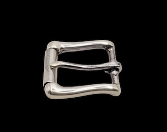 May include: Silver-toned metal belt buckle with a curved design. The buckle has a smooth, polished finish.