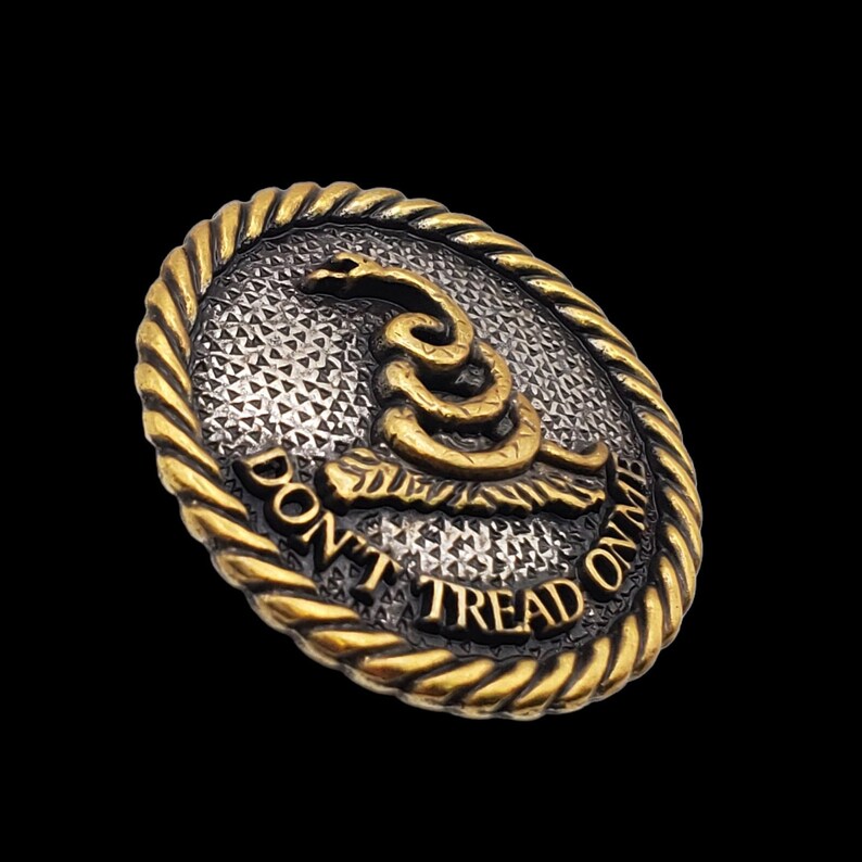 May include: A gold and silver round button with a coiled snake and the text "Don't Tread On Me".
