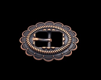 Könnte beinhalten: Eine ovale Metallschnalle mit einem Seil-Design und einem gewellten Rand. Die Schnalle ist kupferfarben und schwarz.